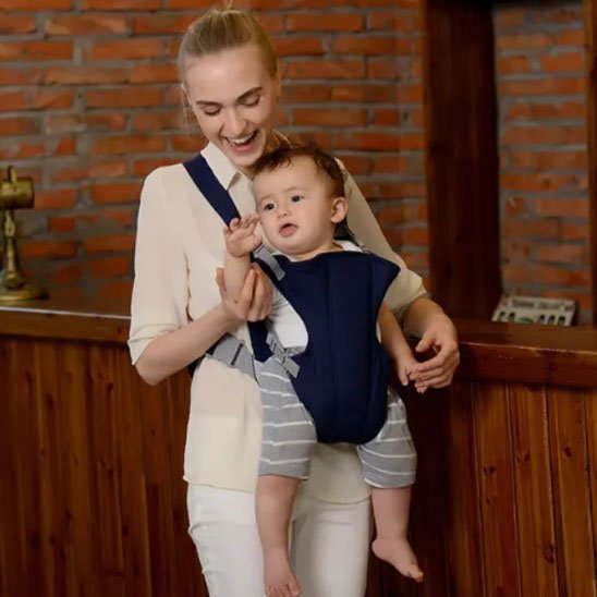 bébé dans son Porte bébé qui souris en jouant avec sa maman